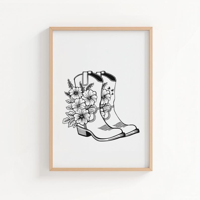 May include: Black and white illustration of two cowboy boots adorned with floral arrangements. The boots are side-by-side, with detailed linework depicting the boot's shape and the flowers' petals and leaves. The artwork is framed in a light wood frame.