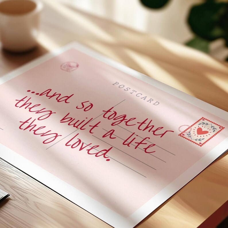 Puede incluir: Una postal rectangular con fondo rosa claro que presenta el texto en cursiva de color rojo oscuro: "...and so together they built a life they loved." La tarjeta incluye la palabra "POSTCARD" en la parte superior derecha y un sello decorativo con un coraz&oacute;n rojo.