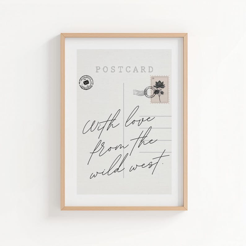 May include: Framed print of a vintage postcard design. The postcard features the word "POSTCARD" at the top, a stamp, and the handwritten phrase "With love from the wild west." The frame is a light brown color.