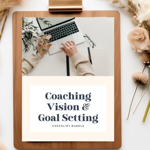 May include: A wooden clipboard holds a white sheet with the text "Coaching Vision & Goal Setting CHECKLIST BUNDLE". A laptop, glasses, and pen are on the white surface. Dried flowers and pampas grass are on the sides.