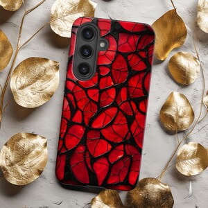 May include: A red and black phone case with a geometric pattern. The case has a camera cutout with three lenses.