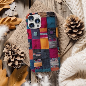 Op de afbeelding: Een kleurrijke telefoonhoes met een patchwork-ontwerp. De hoes heeft een verscheidenheid aan kleuren, waaronder rood, oranje, geel, groen, blauw en paars. De hoes heeft een uitsparing voor de cameralens en een textuur.