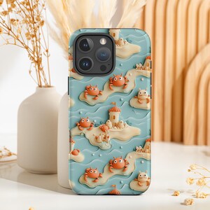May include: A blue and white phone case with a 3D design of crabs and sandcastles. The case has a cutout for the camera lens and a raised lip around the edges to protect the screen.