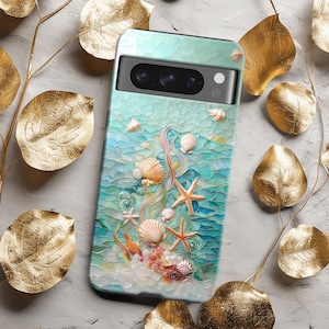 以下が含まれることがあります： 貝殻とヒトデのデザインが施された青と白の携帯電話ケース。ケースにはカメラレンズの切り抜きと白い縁取りがあります。