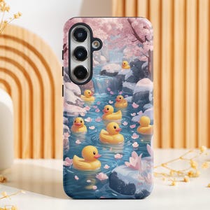 Puede incluir: Una funda de teléfono con un diseño colorido que presenta una cascada, flores de cerezo rosas y patitos de goma amarillos flotando en el agua.