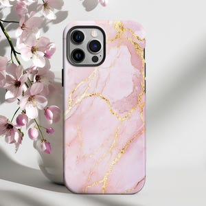Può includere: Custodia per telefono in marmo rosa e oro con bordo bianco. La custodia ha un design in marmo rosa e oro con venature dorate.
