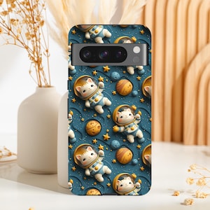 May include: A phone case with a blue background and a repeating pattern of white cats wearing astronaut suits. The cats are floating in space with stars and planets. The case has a black camera cutout.