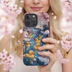 Cute rubber ducks iPhone Case features a sakura stream with playful yellow ducks and floating pink petals for serene, whimsical charm.