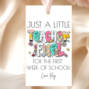May include: A white gift tag with the text "JUST A LITTLE TEACHER FUEL FOR THE FIRST WEEK OF SCHOOL! Love, Ray." The text is in various colors and includes illustrations of school supplies and a coffee cup.