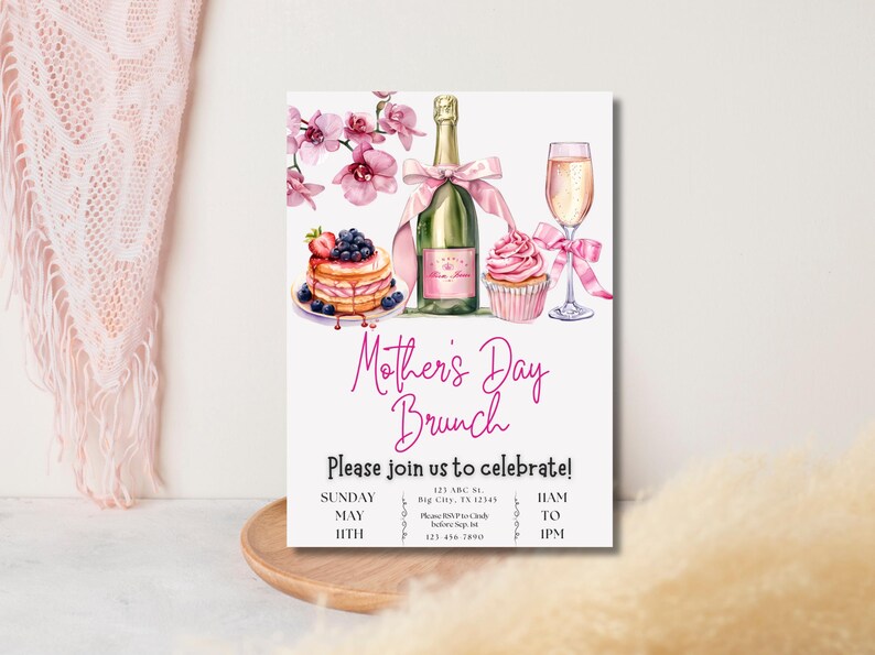 May include: A pink and white Mother's Day brunch invitation with a watercolor illustration of a champagne flute, a bottle of champagne, a cupcake, and a stack of pancakes with blueberries and strawberries. The text reads "Mother's Day Brunch" and "Please join us to celebrate!" with the date and time of the event.