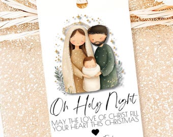 Può includere: Un'etichetta regalo natalizia bianca con un nastro dorato. L'etichetta presenta un'illustrazione di Maria, Giuseppe e Gesù bambino. Il testo sull'etichetta recita "Oh Holy Night" e "Possa l'amore di Cristo riempire il tuo cuore questo Natale."
