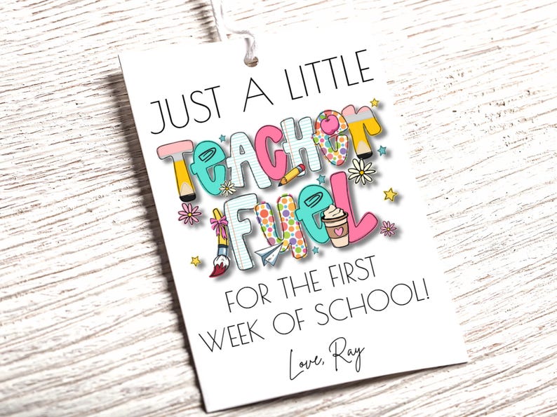 May include: A white gift tag with the text "JUST A LITTLE TEACHER FUEL FOR THE FIRST WEEK OF SCHOOL!" in colorful letters and illustrations. Includes a coffee cup, pencil, and paint brush.