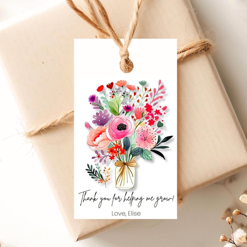 May include: A white gift tag with a colorful floral bouquet illustration. The bouquet is in a mason jar and has pink, red, orange, yellow, purple, and green flowers. The text on the tag reads 'Thank you for helping me grow! Love, Elise'.