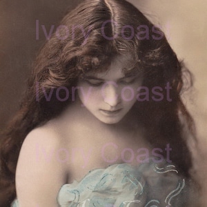 Può includere: Una fotografia vintage in bianco e nero di una donna con i capelli lunghi e ondulati. Indossa un vestito leggero di colore azzurro chiaro e trasparente con un motivo delicato. L'immagine è sbiadita e ha un aspetto vintage.