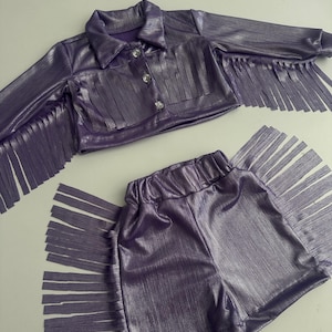 Disfraz de vaquera con flecos lilas: chaqueta vaquera brillante y falda/pantalones cortos para niña.