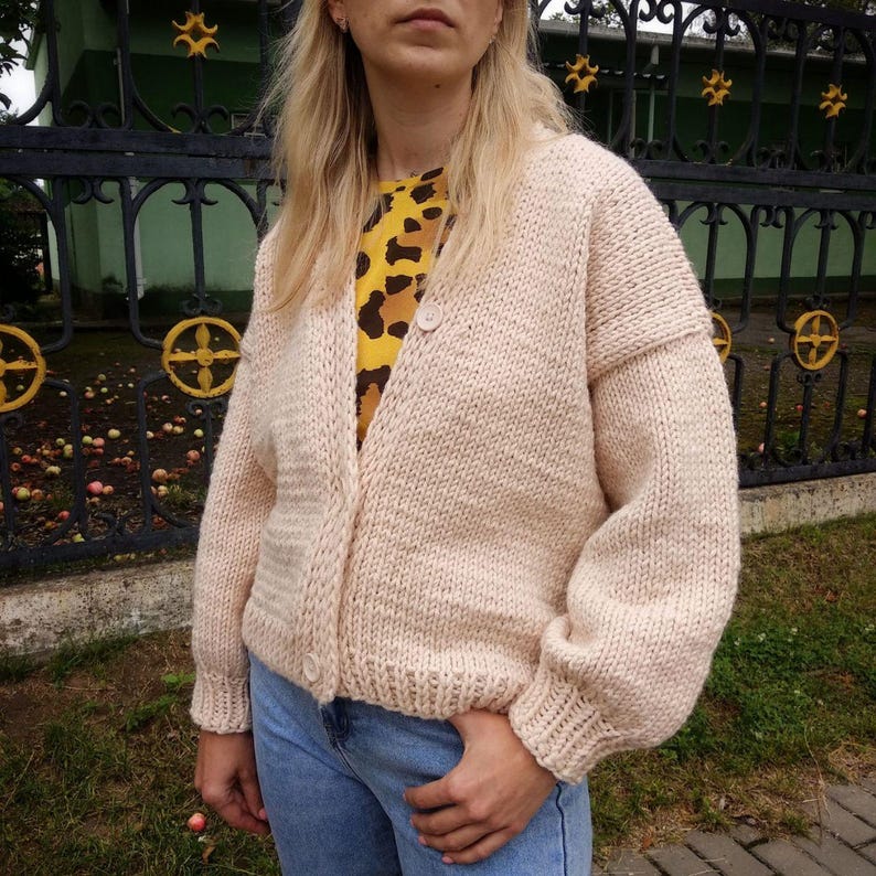 Pode incluir: Um cardigan de malha rosa claro com fecho de bot&atilde;o. O cardigan tem mangas compridas e um caimento solto.