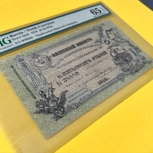 May include: A vintage Russian 50 Rubles banknote from 1918, graded 65. The note features intricate designs, including text in Cyrillic script, a train, and ornate borders. The banknote is encased in a protective holder.