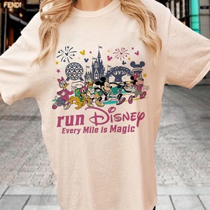 May include: A white t-shirt with a graphic print of Mickey Mouse and other Disney characters running. The text "run Disney Every Mile is Magic" is printed below the graphic.