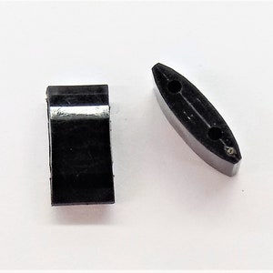 May include: Two black plastic pieces, one rectangular and one oval shaped with two holes.