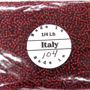 May include: A bag of red seed beads, made in Italy, weighing 1/4 pound. The label also says "Made in Italy" and "104".