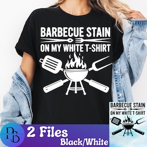 May include: Black t-shirt with a white graphic that reads "BARBECUE STAIN ON MY WHITE T-SHIRT". The graphic includes a grill, spatula, and fork. The bottom of the image has the text "2 Files Black/White".
