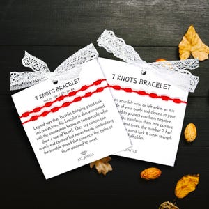 May include: Red and white string bracelet with seven knots. The card reads "7 Knots Bracelet" and includes a description of the bracelet's meaning and symbolism.