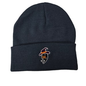 May include: A dark blue beanie with a black and orange embroidered ghost wearing a witch hat.