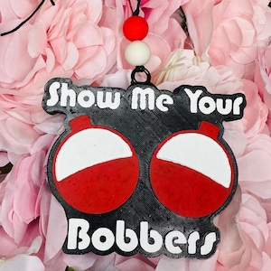 Op de afbeelding: Zwart-wit ornament met rode dobber en de tekst "Show Me Your Bobbers".
