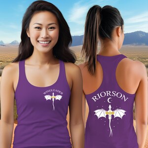 A woman wearing a purple tank top with a dragon design and the text "WINGLEADER" printed on it, standing in front of a desert landscape with mountains in the background.
