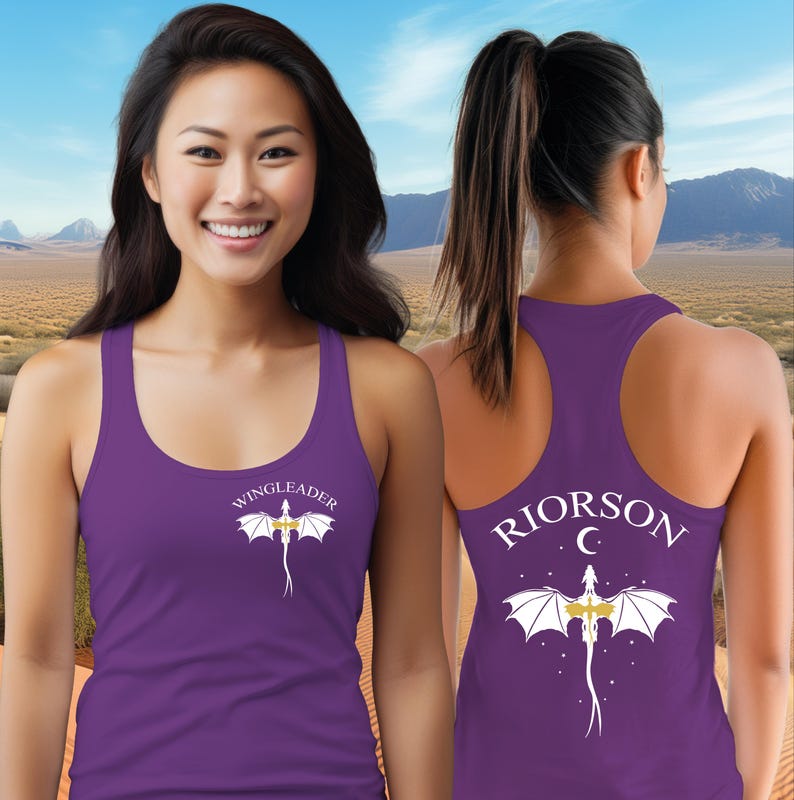 A woman wearing a purple tank top with a dragon design and the text "WINGLEADER" printed on it, standing in front of a desert landscape with mountains in the background.