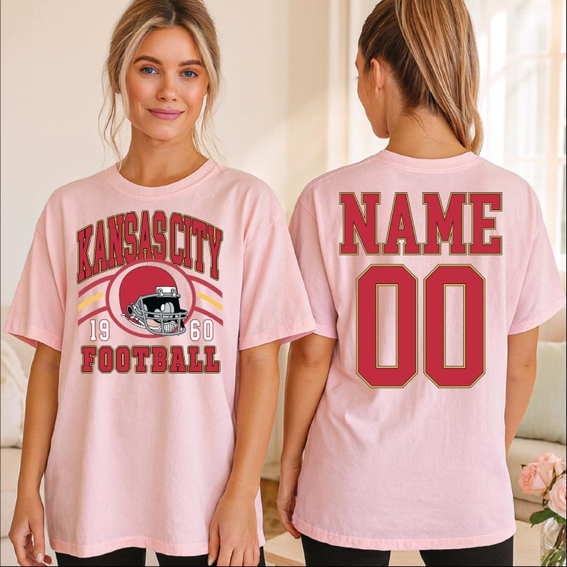 A woman wearing a pink t-shirt with a graphic of a football helmet and the text "KANSAS CITY FOOTBALL" printed on it.