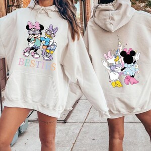 two people wearing white hooded sweatshirts with Minnie Mouse and Donald Duck printed on them.
