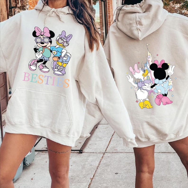 two people wearing white hooded sweatshirts with Minnie Mouse and Donald Duck printed on them.