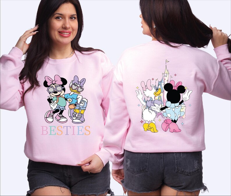 A woman wearing a pink sweatshirt with Minnie Mouse and other Disney characters printed on it.