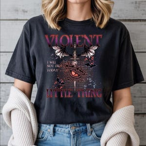 A person wearing a black t-shirt with a graphic design featuring a dragon, text, and a quote.