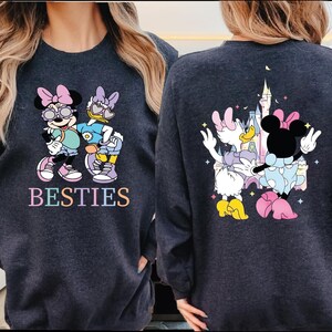 two people wearing matching sweatshirts with a cartoon character design.