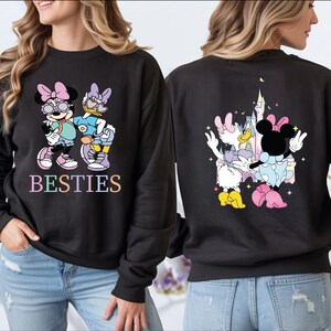 A woman wearing a black sweatshirt with a colorful design featuring Minnie Mouse and Donald Duck.