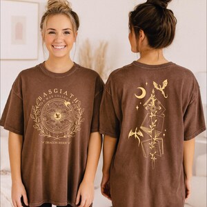 Two women wearing brown t-shirts with a graphic design on the front and back.
