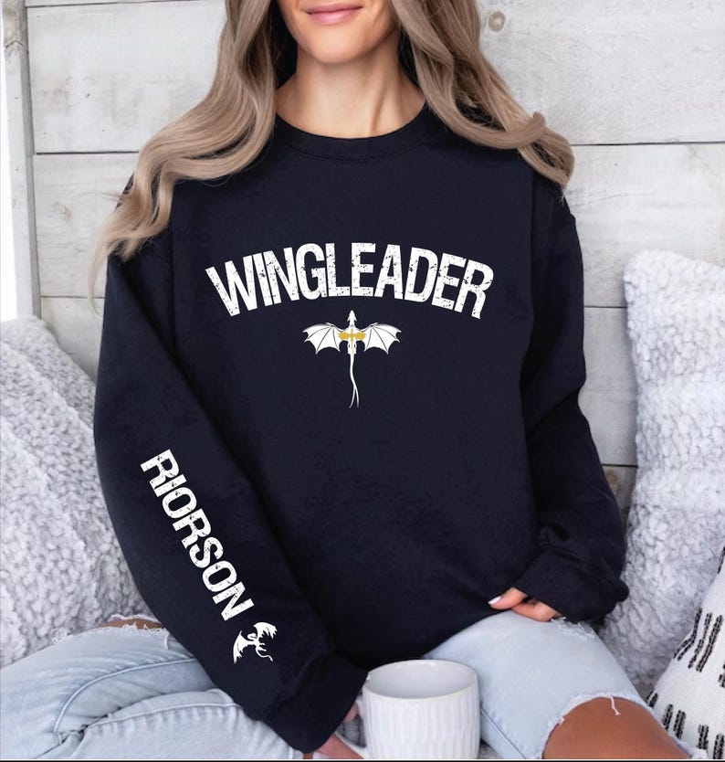 a woman sitting on a bed wearing a black sweater