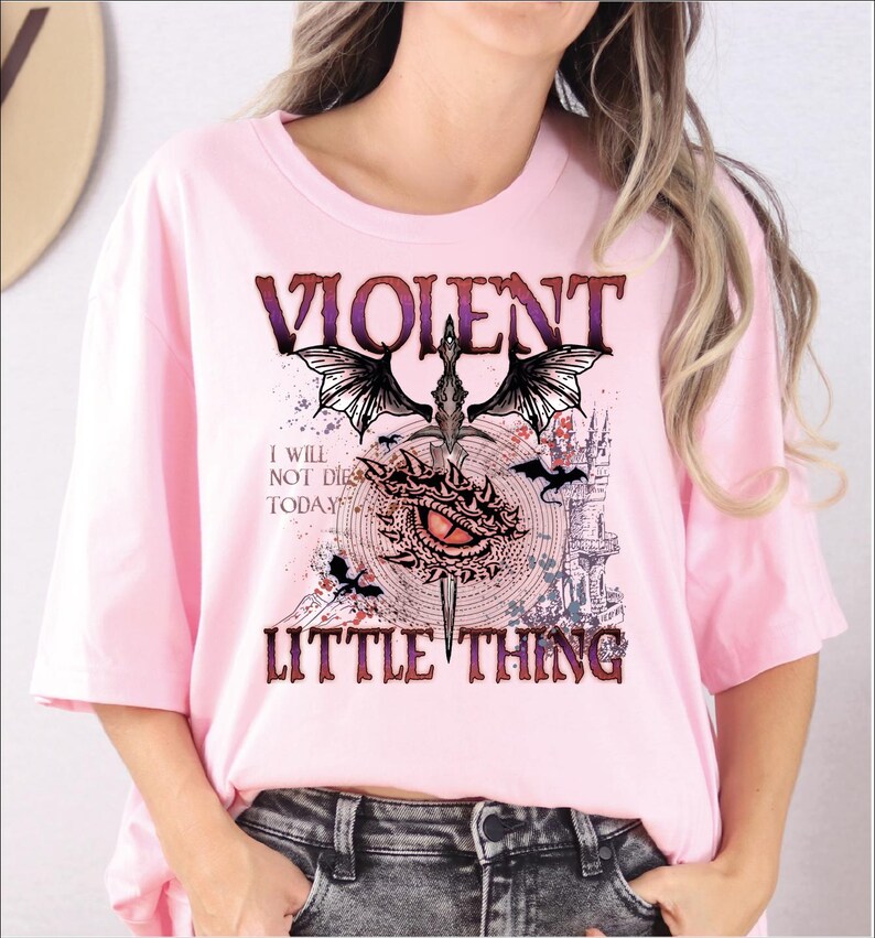 A woman wearing a pink t-shirt with a graphic design featuring a dragon, castle, and text.