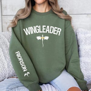 a woman sitting on a couch wearing a green sweatshirt