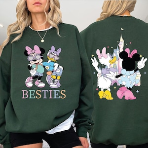 A woman wearing a green sweatshirt with a cartoon image of Minnie Mouse and Donald Duck on the front, and a castle on the back.