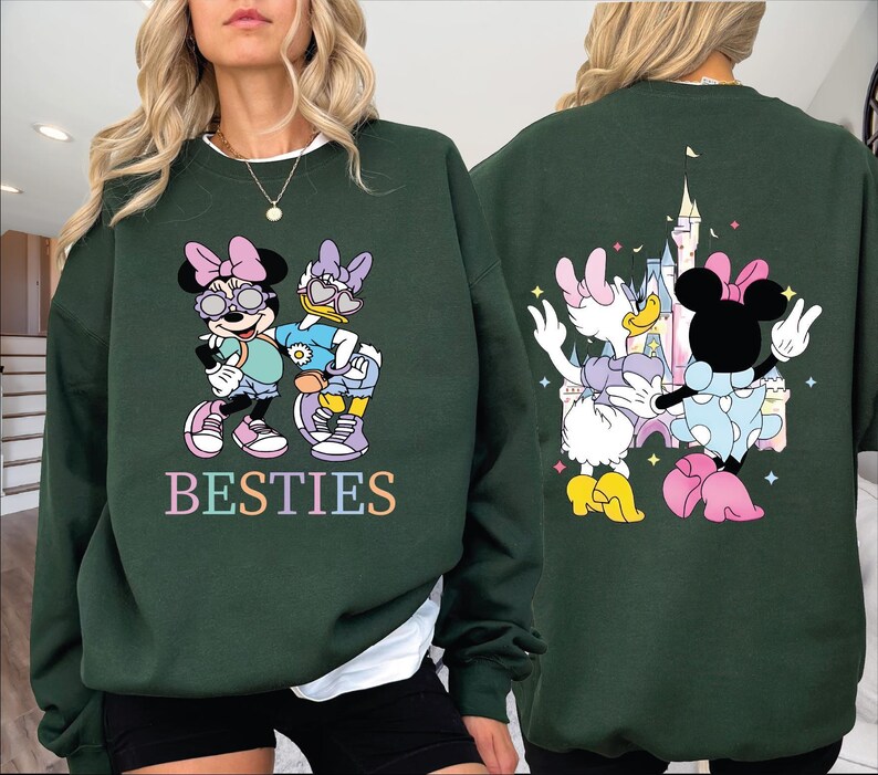 A woman wearing a green sweatshirt with a cartoon image of Minnie Mouse and Donald Duck on the front, and a castle on the back.