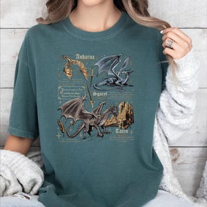 A woman wearing a green t-shirt with a graphic design of two dragons and text that appears to be a description or information about the dragons.