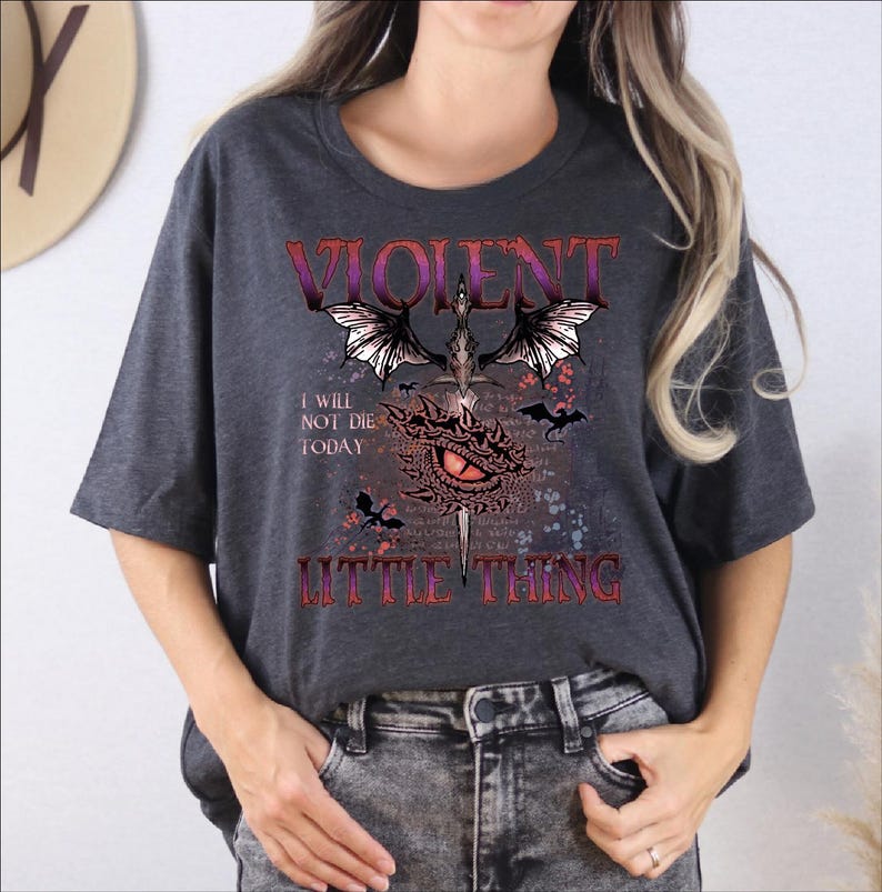 A woman wearing a gray t-shirt with a graphic design featuring a dragon, text, and a quote.