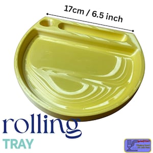 Puede incluir: Una bandeja rodante amarilla con un diseño curvo, que mide 17 cm (6,5 pulgadas) de diámetro. Cuenta con un soporte incorporado y una sección dividida. La palabra "rolling" está impresa en azul oscuro, con "TRAY" debajo.