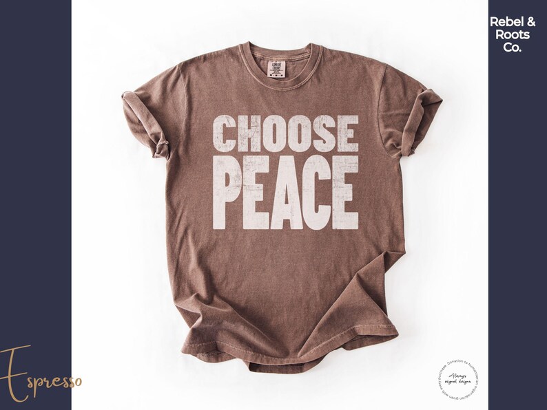 May include: A short-sleeved crew neck t-shirt in a solid espresso brown color. The front of the shirt features the text CHOOSE PEACE printed in a large, distressed, off-white block font. The garment has a standard fit with rolled sleeves.