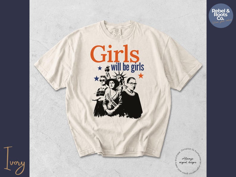 May include: Ivory-colored t-shirt with the text "Girls will be girls" in orange and blue, along with star graphics. The shirt features a black and white graphic of three women, including the Statue of Liberty.