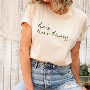 a woman sitting on a stool wearing a t - shirt that says be hunting
