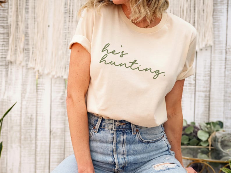a woman sitting on a stool wearing a t - shirt that says be hunting